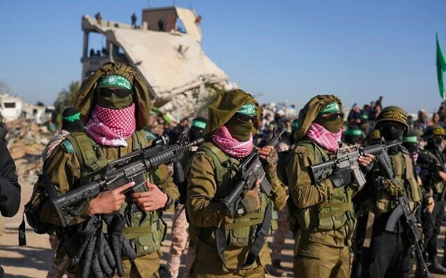 חמושי חמאס, לבושים במדי צה"ל שנתפסו ומניפים נשק ישראלי, עומדים במסדר בחאן יונס שבדרום רצועת עזה, 15 בפברואר 2025