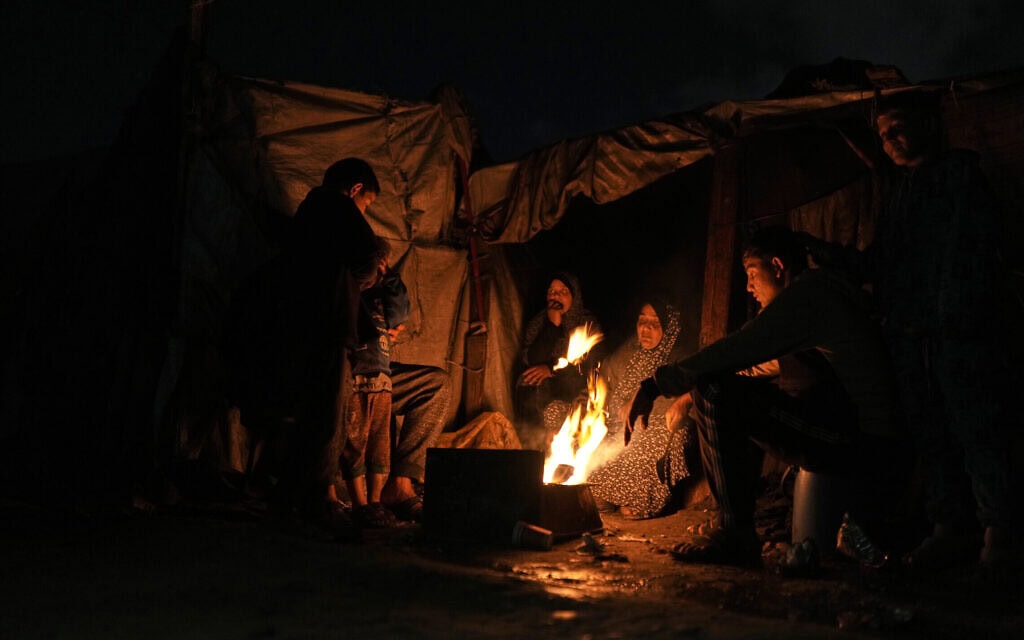 פלסטינים עקורים מתחממים סביב מדורה במחנה אוהלים בעיר עזה, 18 בינואר 2026 (צילום: AP Photo/Jehad Alshrafi) פלסטינים עקורים מתחממים סביב מדורה במחנה אוהלים בעיר עזה, 18 בינואר 2026 (צילום: AP Photo/Jehad Alshrafi)
