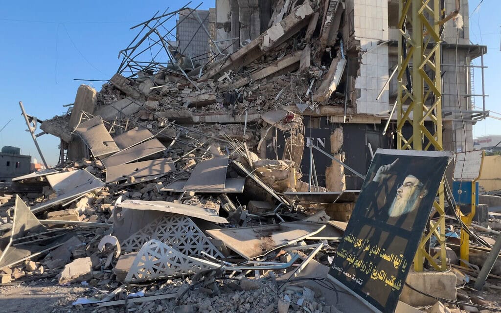דיוקנו של חסן נסראללה ליד בניין שנהרס בתקיפות ישראליות בבנק  של אגודת אל-קרד&nbsp;אל-חסן המקושר לחזבאללה. 10 במרץ 2026 (צילום: AP Photo/Hussein Malla)