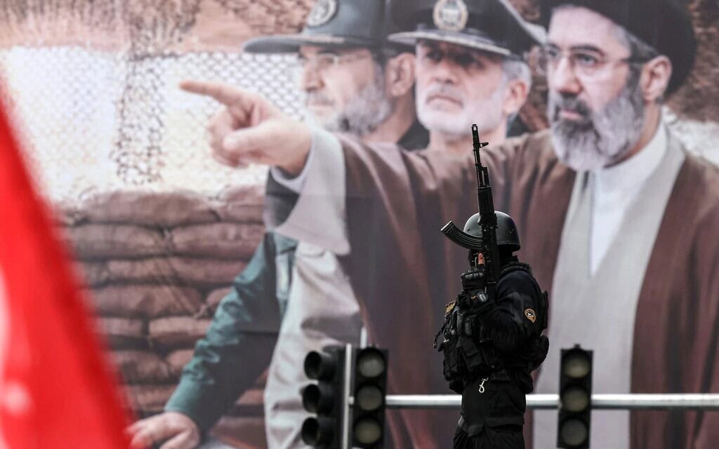 קצין איראני עומד על המשמר לצד שלט חוצות גדול של המנהיג העליון החדש של איראן, האייתוללה מוג'תבא חמינאי, במהלך עצרת יום אל־קודס (ירושלים), 13 במרץ 2026 (צילום: AFP) קצין איראני עומד על המשמר לצד שלט חוצות גדול של המנהיג העליון החדש של איראן, האייתוללה מוג'תבא חמינאי, במהלך עצרת יום אל־קודס (ירושלים), 13 במרץ 2026 (צילום: AFP)