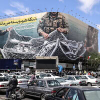 כלי רכב חולפים לצד שלט חוצות גדול שעליו נכתב "מצר הורמוז נותר סגור", בעת שאנשים מתאספים בכיכר המהפכה בטהרן לאחר שארצות הברית ואיראן הסכימו על הפסקת אש בת שבועיים, ב-8 באפריל 2026