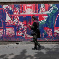 אישה חולפת על פני ציור קיר אנטי־אמריקאי המצויר על קיר שגרירות ארה"ב לשעבר בטהרן, איראן, 25 באפריל 2026