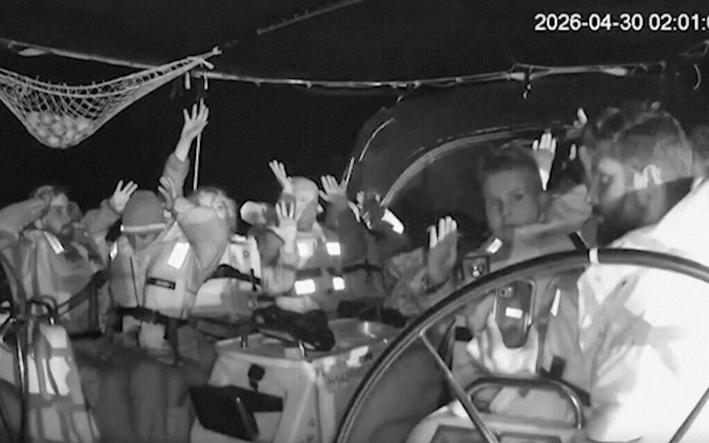 תצלום מתוך תיעוד מצלמות אבטחה בשחור־לבן מציג משתתפים על סיפון ספינת מהמשט סומוד כשהם מרימים ידיים. 30 באפריל 2026 (צילום: Global Sumud Flotilla via AP)