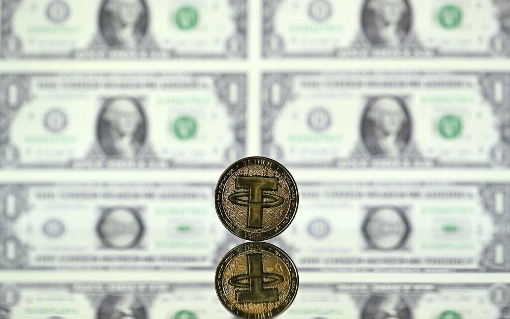 אילוסטרציה: המטבע היציב טתר (USDT) על רקע שטרות דולר אמריקאי (צילום: Justin TALLIS / AFP) אילוסטרציה: המטבע היציב טתר (USDT) על רקע שטרות דולר אמריקאי (צילום: Justin TALLIS / AFP)