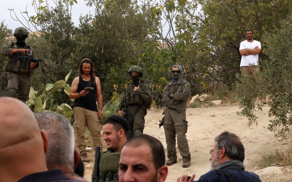 חיילים ומתנחלים מתאספים בכפר איד’נא, מצפון לעיר חברון שבגדה המערבית, במהלך עונת מסיק הזיתים, ב-12 באוקטובר 2025 (צילום: HAZEM BADER / AFP) חיילים ומתנחלים מתאספים בכפר איד’נא, מצפון לעיר חברון שבגדה המערבית, במהלך עונת מסיק הזיתים, ב-12 באוקטובר 2025 (צילום: HAZEM BADER / AFP)