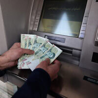 אזרח איראני מושך כסף מכספומט של בנק בטהרן. 7 בינואר 2026