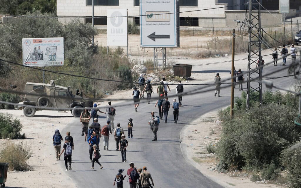 כוח צה"ל מאבטח את הכביש בעת שמתנחלים צועדים בכפר הפלסטיני תל שבגדה המערבית, סמוך לשכם. 31 ביולי 2026 (צילום: AP Photo/Majdi Mohammed)