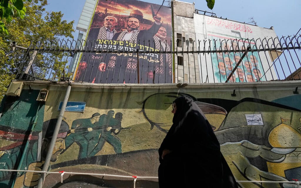 אישה צועדת בטהרן מתחת לשלט המציג את מנהיג חמאס הנבחר, חליל אל-חיה (במרכז), לצד המנהיגים המנוחים אסמאעיל הנייה (מימין) ויחיא סנוואר. 1 באוגוסט 2026 (צילום: AP Photo/Vahid Salemi) אישה צועדת בטהרן מתחת לשלט המציג את מנהיג חמאס הנבחר, חליל אל-חיה (במרכז), לצד המנהיגים המנוחים אסמאעיל הנייה (מימין) ויחיא סנוואר. 1 באוגוסט 2026 (צילום: AP Photo/Vahid Salemi)