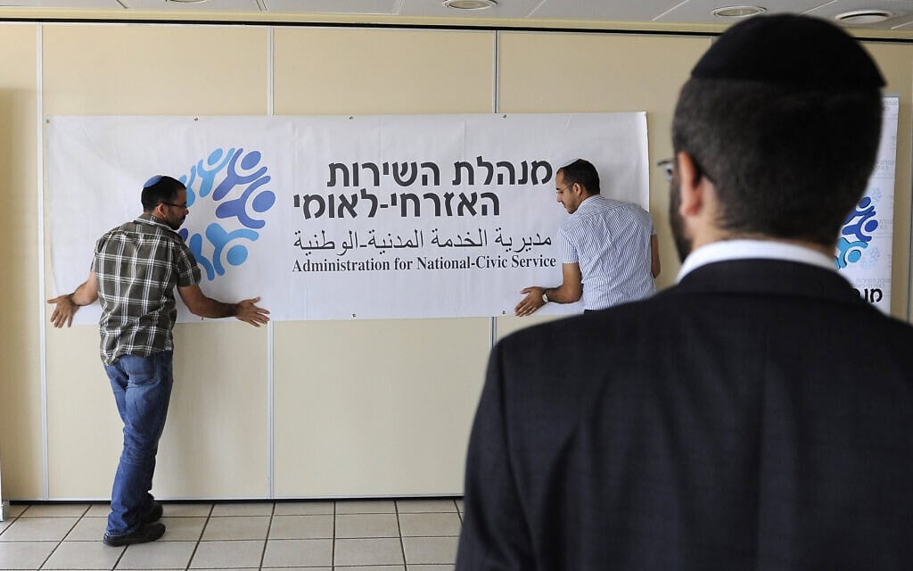 גבר חרדי מתבונן בהתקנת שלט של מנהלת השירות הלאומי לקראת דיון בנושא גיוס חרדים לצה"ל עם שר הכלכלה נפתלי בנט, בבניין יד שרה בירושלים. 11 ביוני 2013 (צילום: Zuzana Janku/Flash90) גבר חרדי מתבונן בהתקנת שלט של מנהלת השירות הלאומי לקראת דיון בנושא גיוס חרדים לצה"ל עם שר הכלכלה נפתלי בנט, בבניין יד שרה בירושלים. 11 ביוני 2013 (צילום: Zuzana Janku/Flash90)