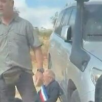 צילום מסך מתוך תיעוד שהופץ ברשתות החברתיות מציג גבר עוטה אבנט כחול-לבן-אדום, מהסוג המשמש נבחרי ציבור בצרפת, נשען על כלי רכב בעוד רעולי פנים חוסמים ומכתרים מכונית שבה נסעו פעילים בכפר הנוצרי טייבה שבגדה המערבית. 17 באוקטובר 2026 (צילום: UGC / AFP) צילום מסך מתוך תיעוד שהופץ ברשתות החברתיות מציג גבר עוטה אבנט כחול-לבן-אדום, מהסוג המשמש נבחרי ציבור בצרפת, נשען על כלי רכב בעוד רעולי פנים חוסמים ומכתרים מכונית שבה נסעו פעילים בכפר הנוצרי טייבה שבגדה המערבית. 17 באוקטובר 2026 (צילום: UGC / AFP)