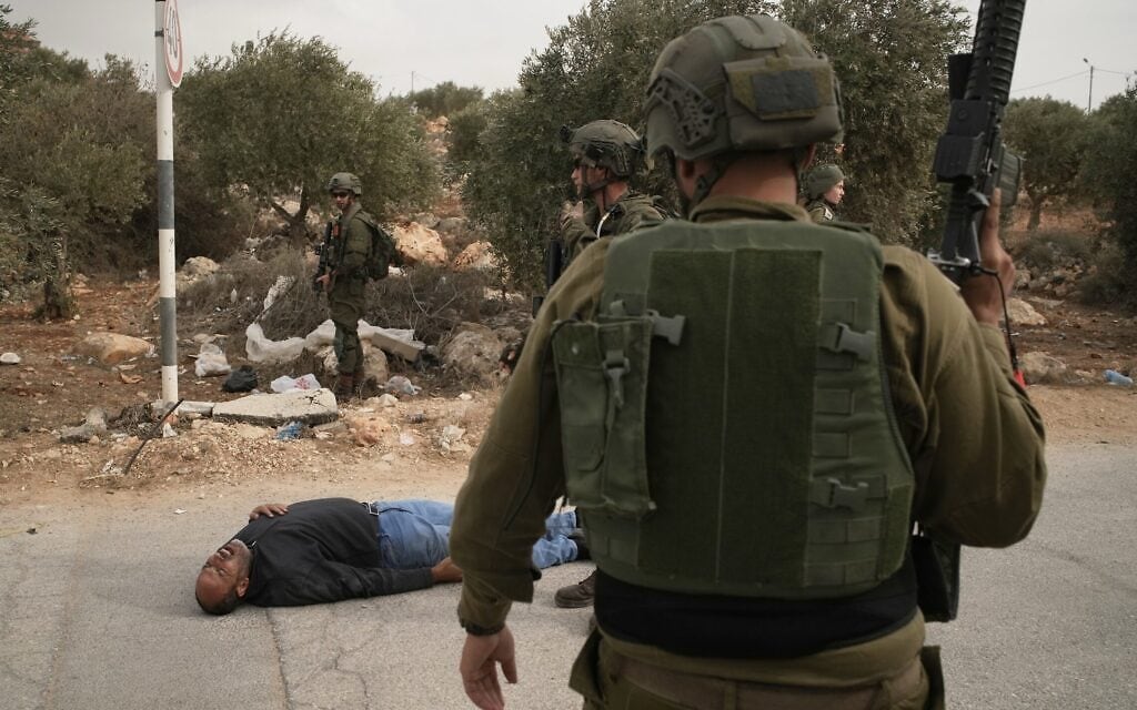 חיילים ישראלים עומדים לצד פלסטיני פצוע השרוע על הכביש לאחר שנורה בידי חיילים, בעקבות תקיפת מתנחלים נגד פלסטינים בעת מסיק זיתים בכפר אבו פלאח שבגדה המערבית. 16 באוקטובר 2026 (צילום: AP Photo/Leo Correa) חיילים ישראלים עומדים לצד פלסטיני פצוע השרוע על הכביש לאחר שנורה בידי חיילים, בעקבות תקיפת מתנחלים נגד פלסטינים בעת מסיק זיתים בכפר אבו פלאח שבגדה המערבית. 16 באוקטובר 2026 (צילום: AP Photo/Leo Correa)