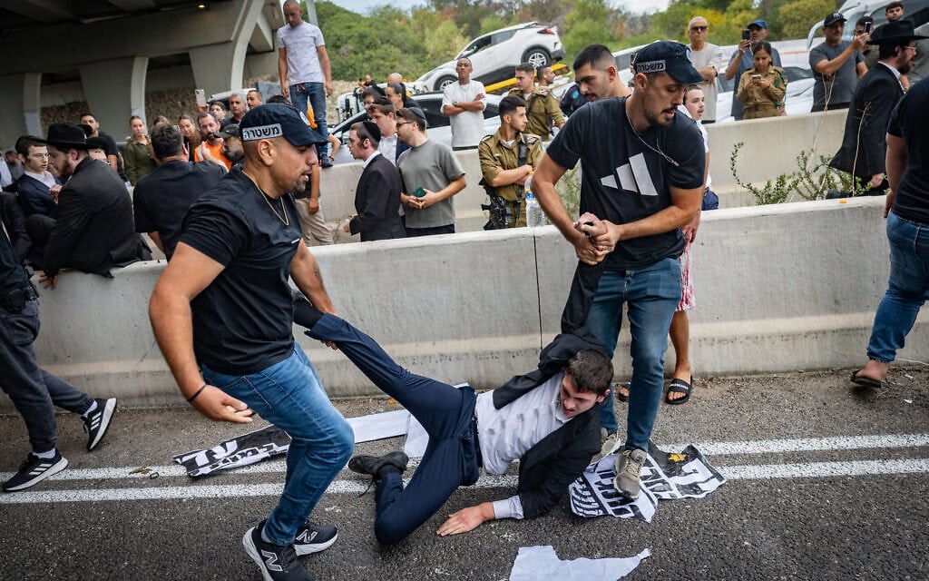 עימותים בין גברים חרדים לשוטרים ולאזרחים בעת חסימת כביש במחאה על כליאתם של תלמידי ישיבה שלא התייצבו לגיוס לצה"ל, במחלף יבנה בכביש 4. 18 באוקטובר 2026 (צילום: חיים גולדברג/פלאש90)